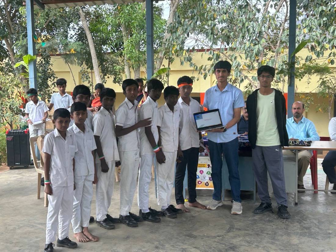 Vihaan holding a laptop beside a line of students in school uniform at a Project Setu Republic Day programme