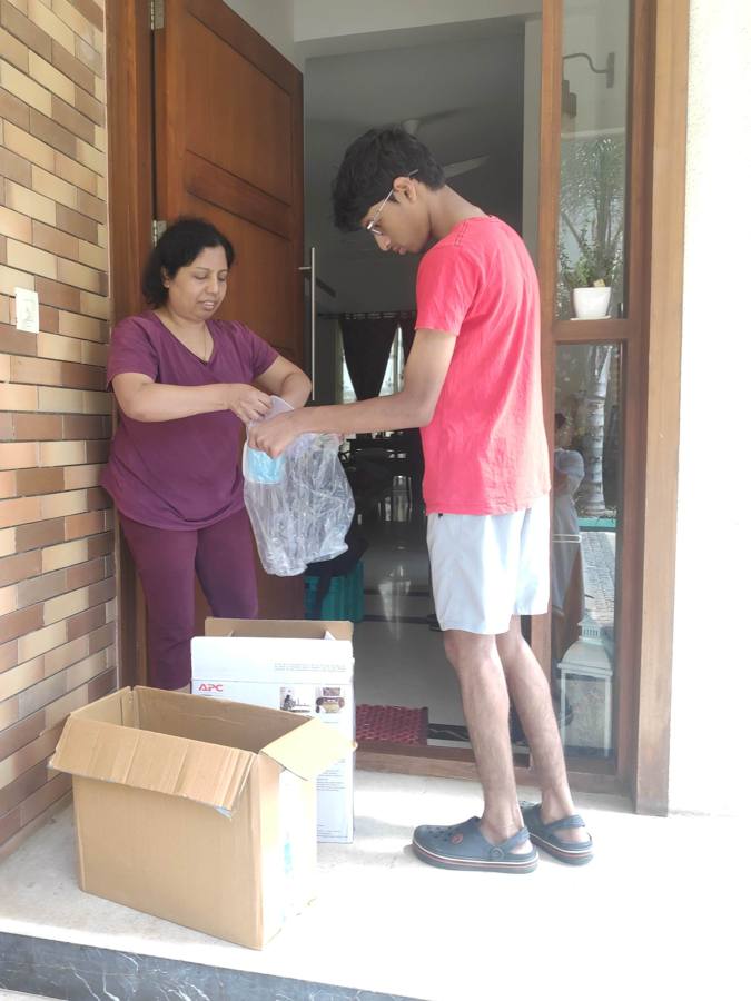 Vihaan and a resident packing e-waste into boxes at a front door